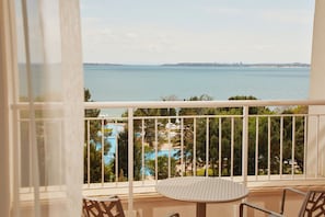 A balcony with a view of a body of water and a pool.