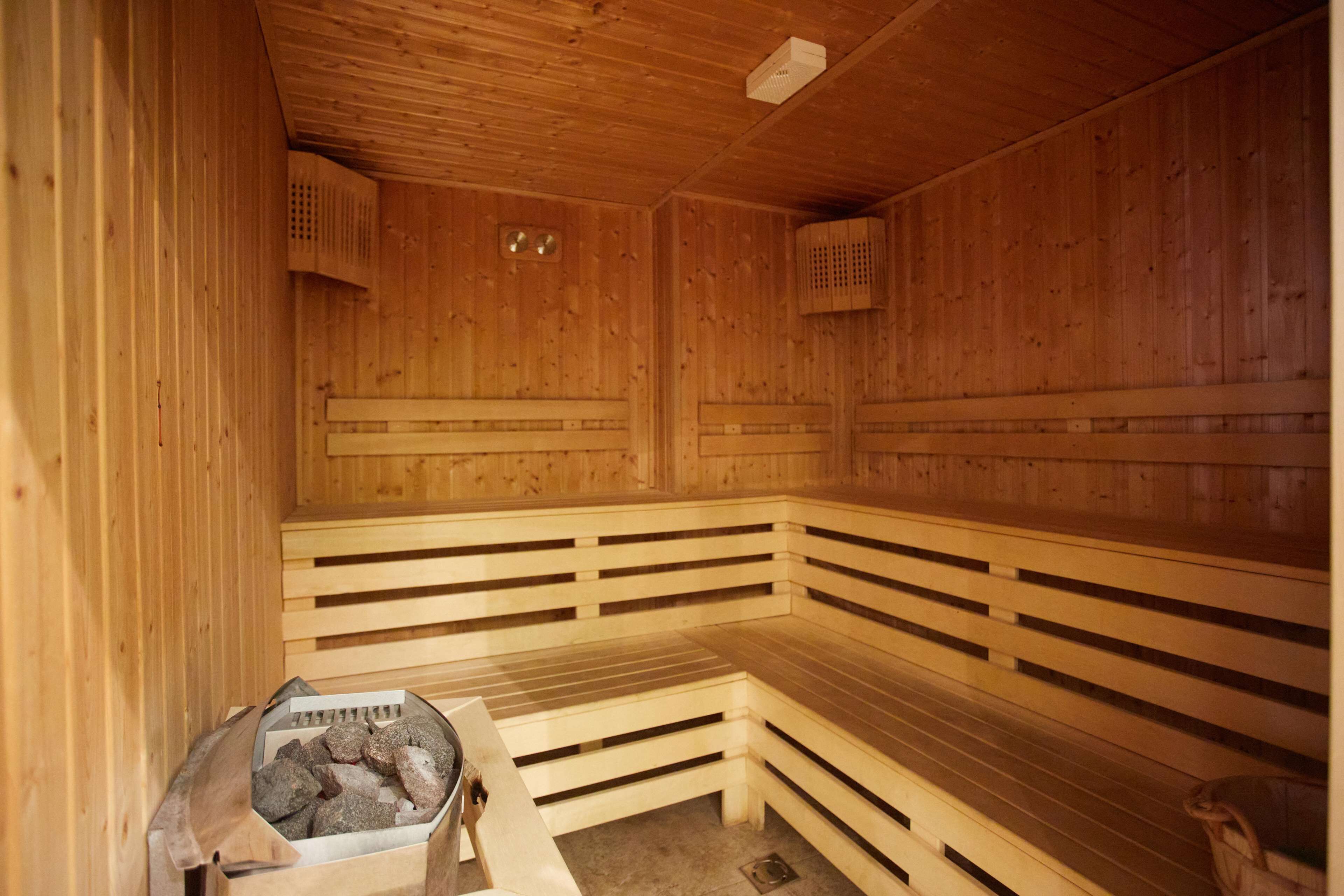 A wooden sauna with benches and a stone heater.