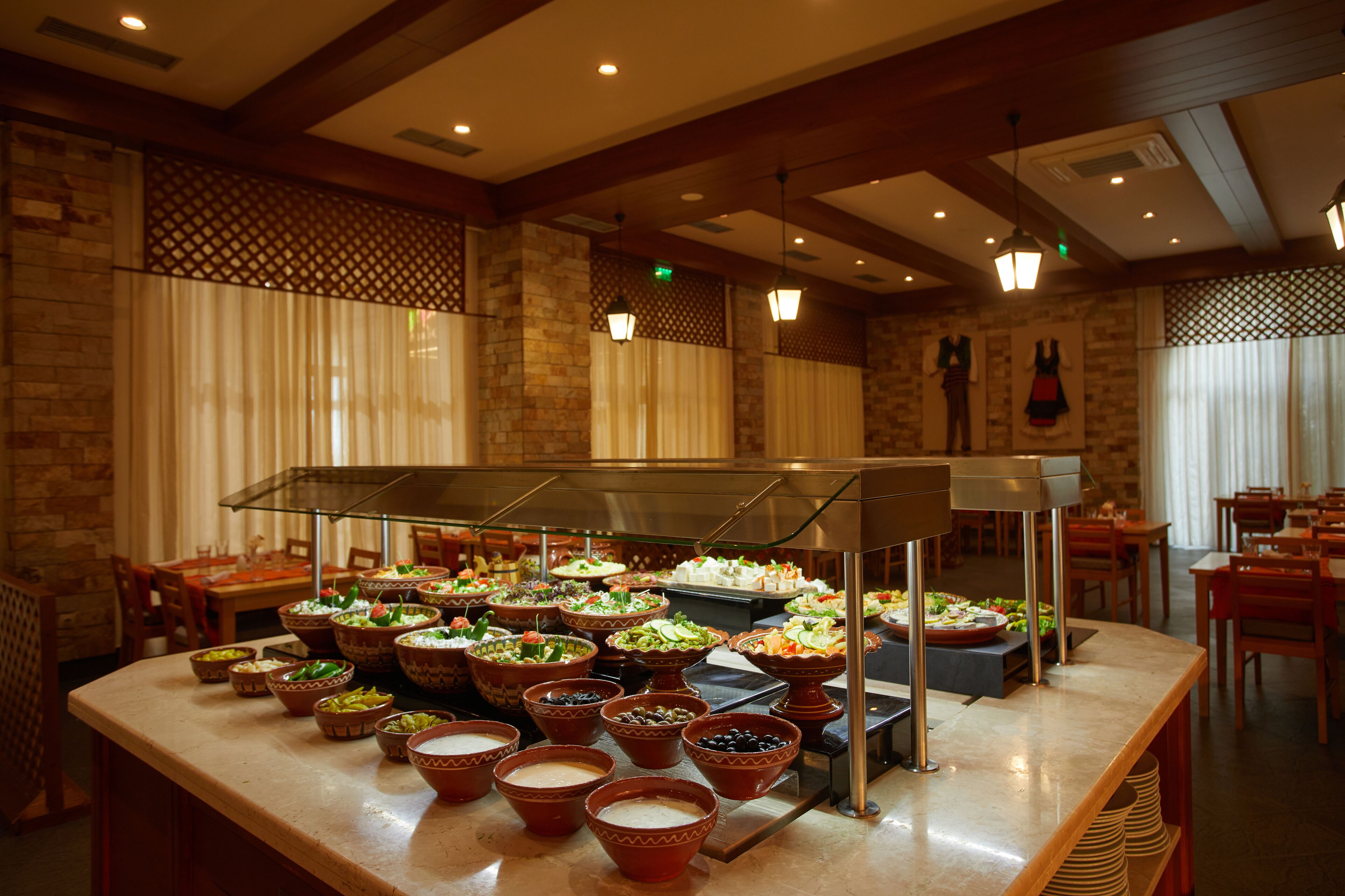 A buffet area with various food dishes displayed in bowls and platters, with a counter and seating area in the background.