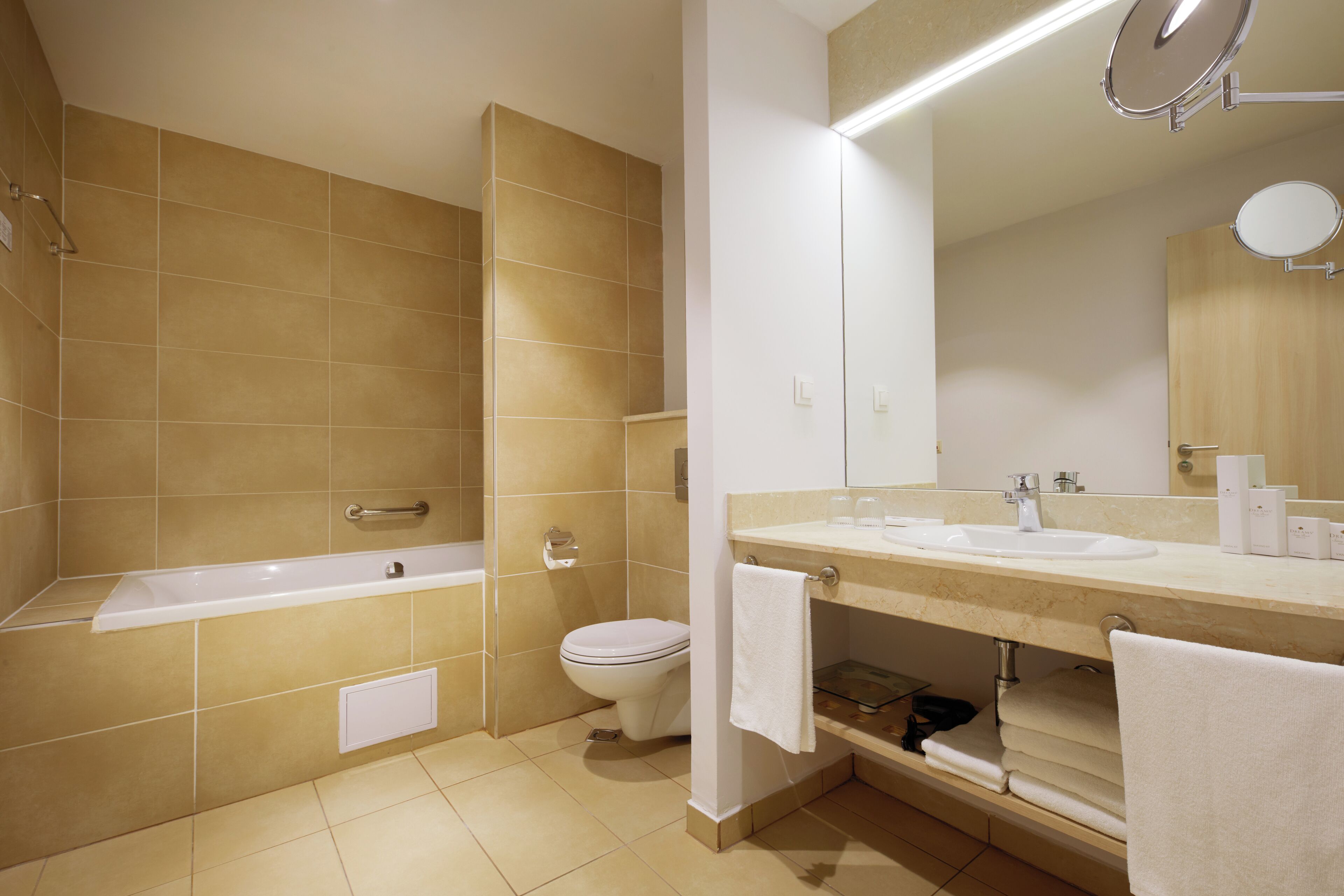 A modern bathroom with a bathtub, toilet, and vanity with a mirror.