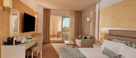Une chambre d’hôtel avec un lit, un bureau avec un ordinateur, une chaise, une petite table et un balcon avec vue.