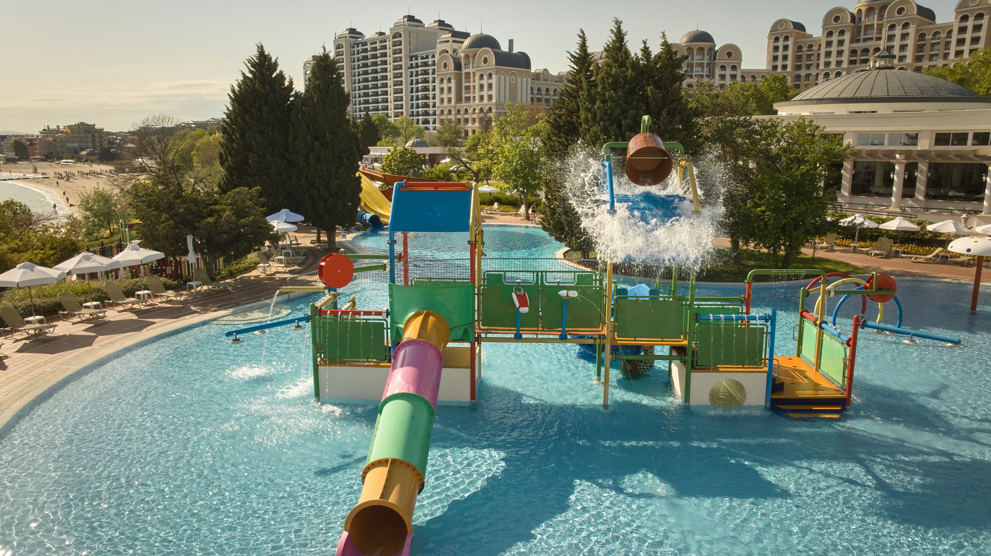 A water park with slides and a pool, surrounded by buildings and trees.