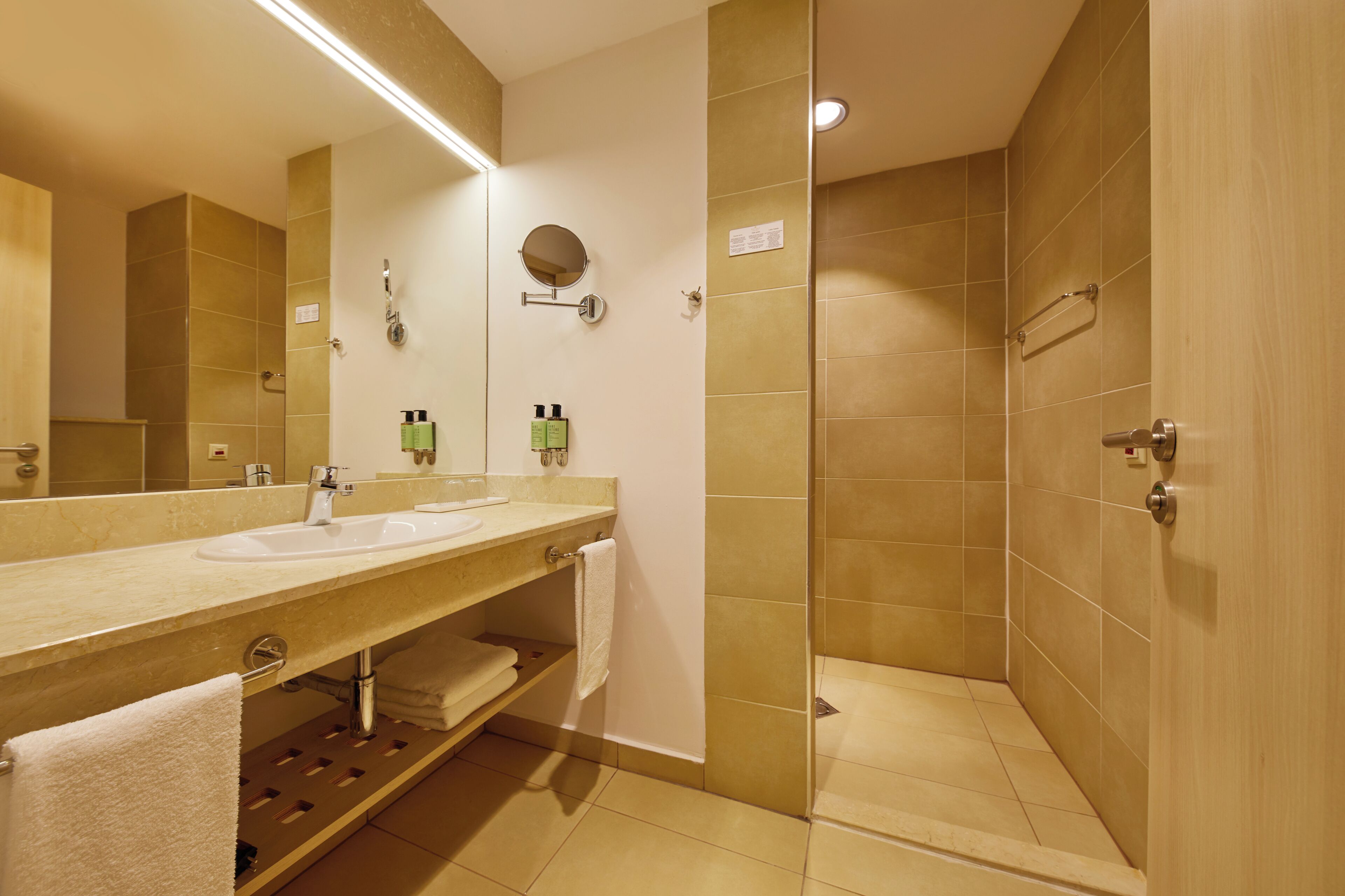 A bathroom with two sinks, a mirror, a towel rack, and a shower area.