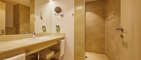 A bathroom with two sinks, a mirror, a towel rack, and a shower area.