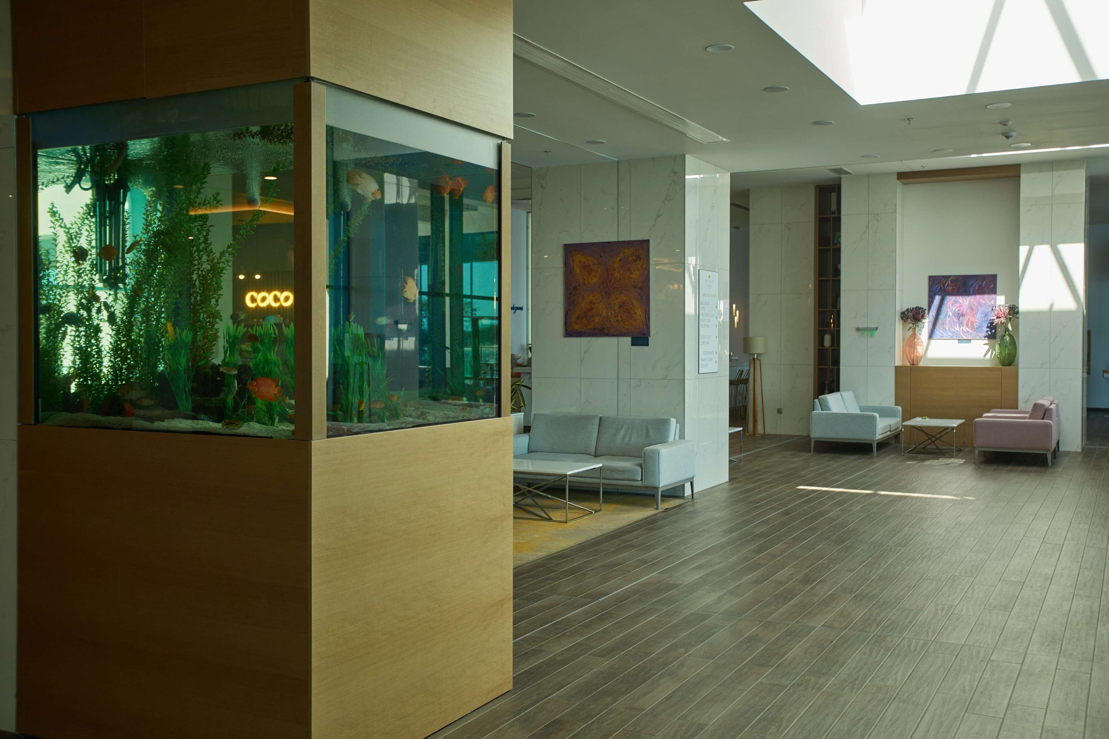 A modern lobby with a large aquarium, seating areas, and artwork on the walls.