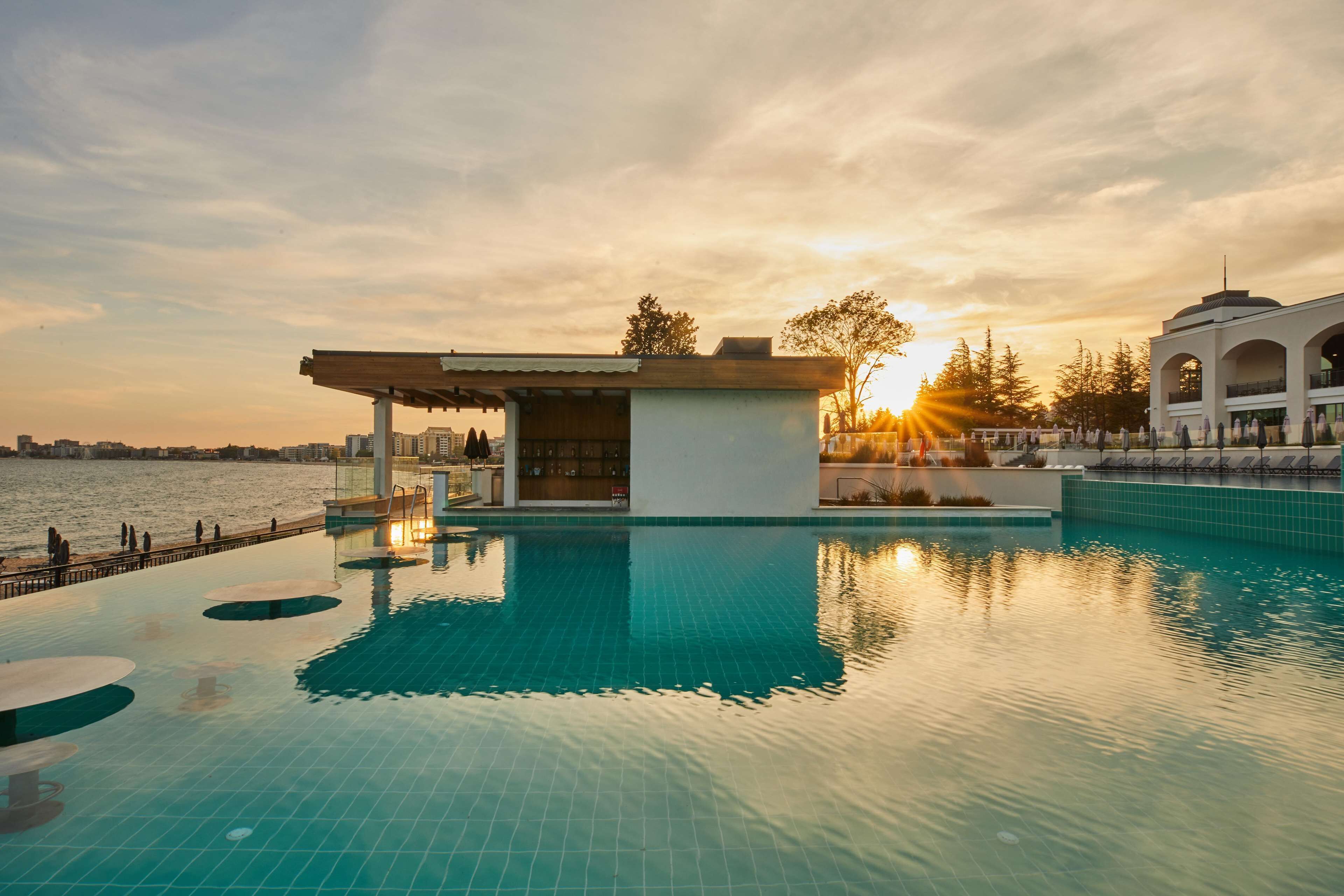 A swimming pool with a sunlit sky and a view of the city skyline.