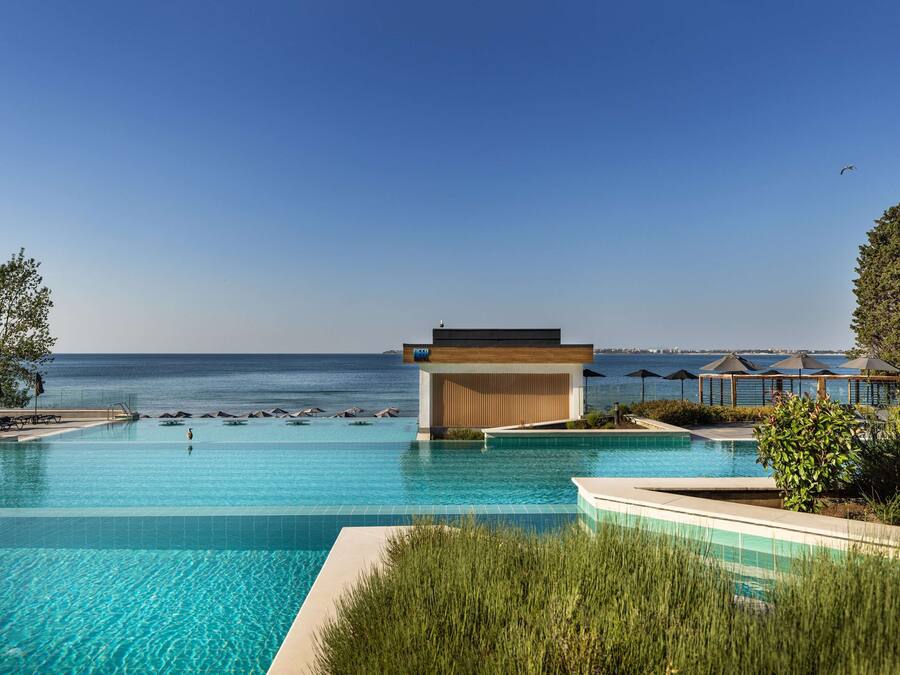 Una piscina techada, una piscina al aire libre, sombrillas