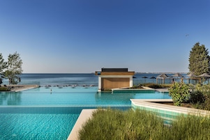 Una piscina techada, una piscina al aire libre, sombrillas