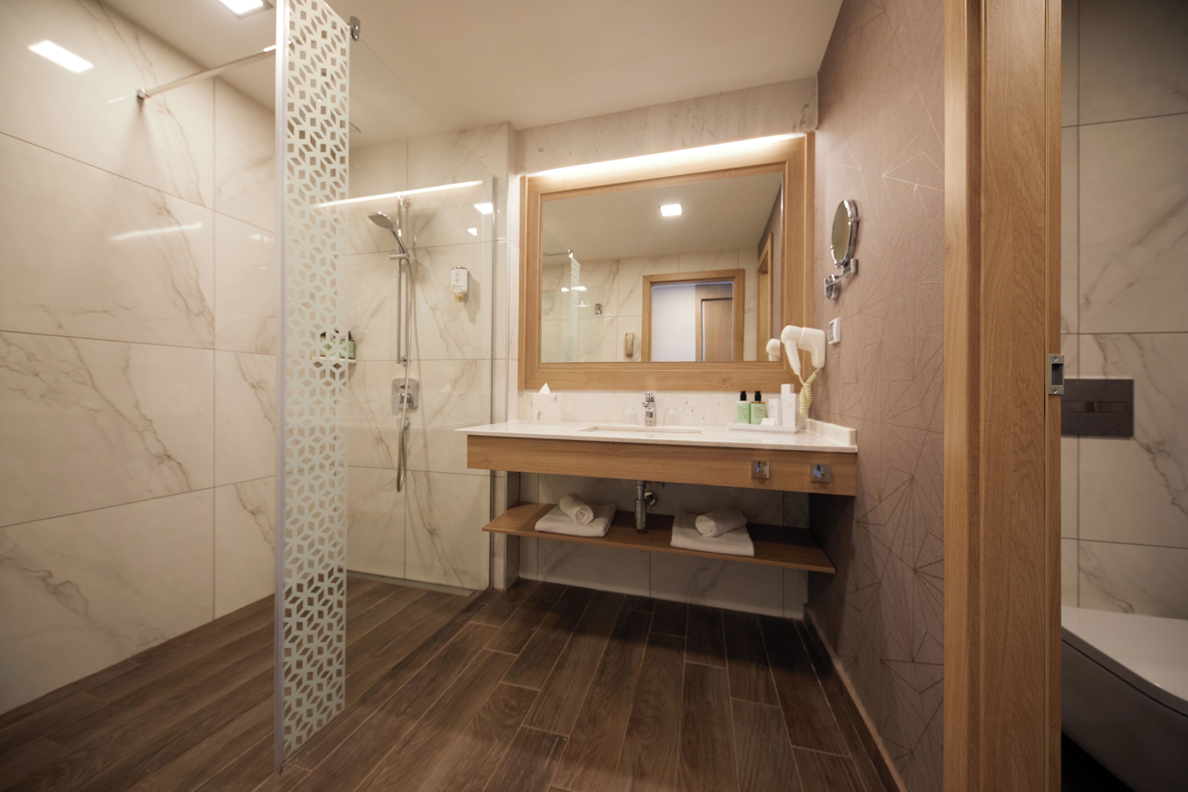 Une salle de bain moderne avec une douche, un lavabo avec un miroir et un meuble-lavabo en bois.