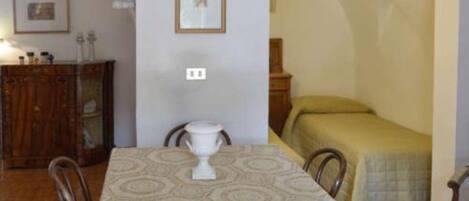 Una habitación con una mesa de comedor, sillas, una cama y un armario.