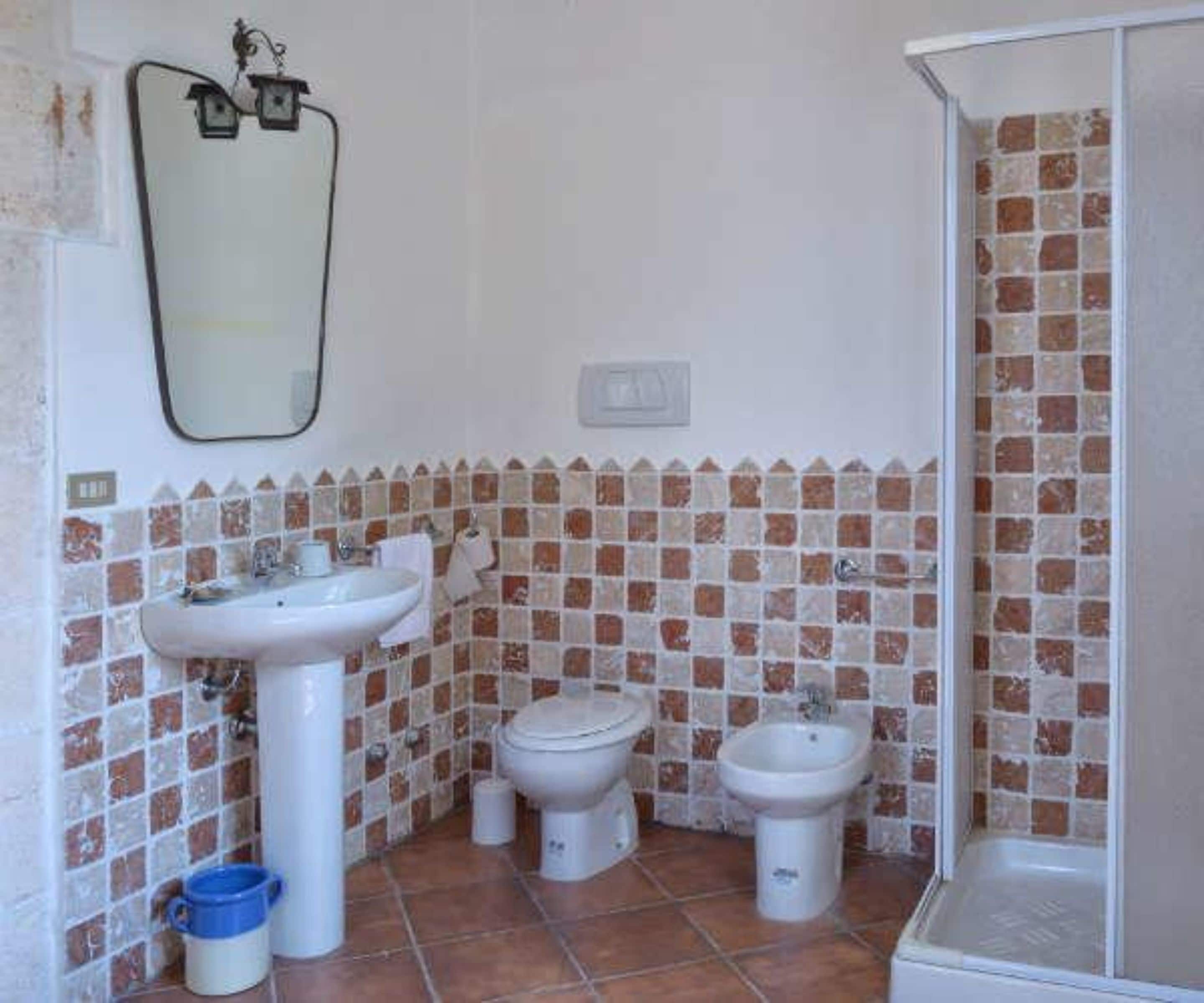 A bathroom with a sink, toilet, bidet, and shower.