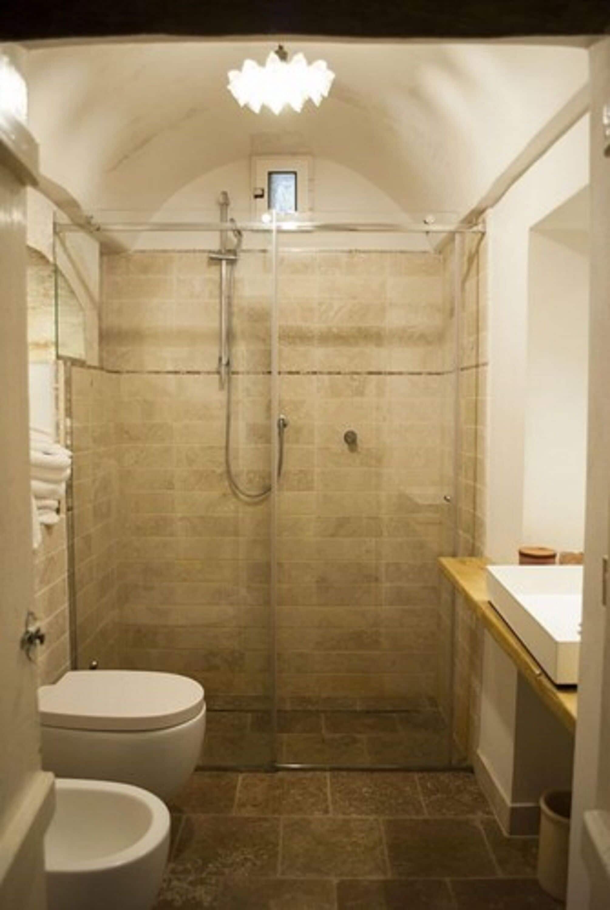 A small, enclosed bathroom with a shower, toilet, and sink.
