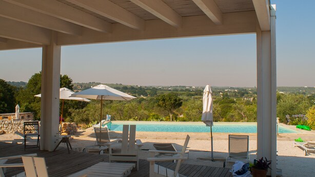 A covered outdoor area with a pool, lounge chairs, and umbrellas. - Agriturismo Antonelli Piangevino (Monopoli)