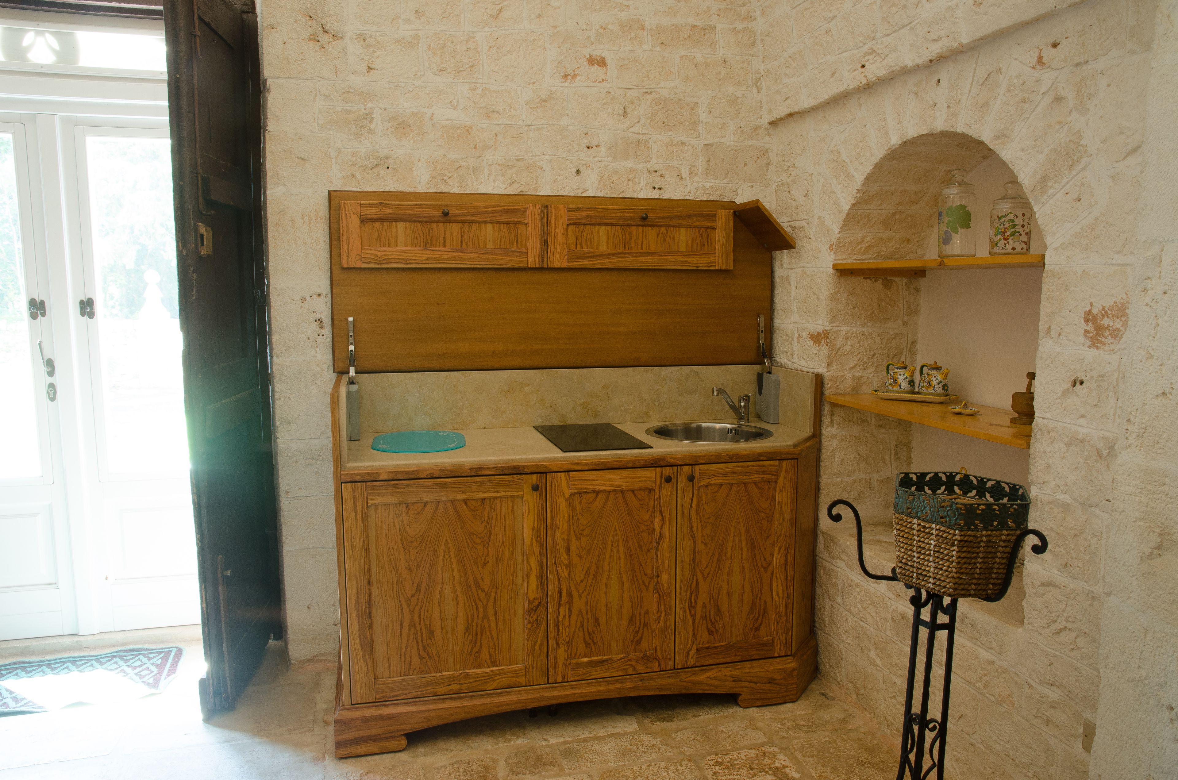 A kitchen with wooden cabinets, a sink, and a small shelf with jars.