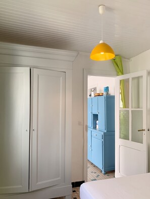 A room with a white door, a blue wardrobe, and a bed with a white bedspread. - Homerez - Charming House Soulac-sur-Mer, Garden, 65 m² (Soulac-sur-Mer)