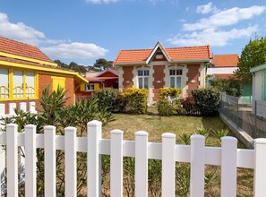 A residential area with houses, a white picket fence, and a clear sky. - Homerez - Charming House Soulac-sur-Mer, Garden, 65 m² (Soulac-sur-Mer)