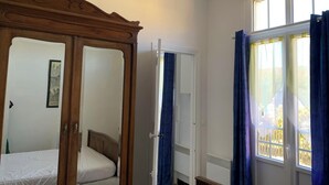 Une chambre avec un lit à baldaquin en bois, une porte blanche et une fenêtre ornée de rideaux bleus.