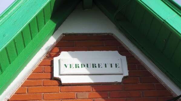 A brick pathway leading to a white sign with the word "VERDURETTE" on it.