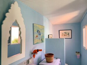 A bathroom with a blue wall, a white ceiling, and a window. There are three framed pictures on the wall. - Homerez - Charming House Soulac-sur-Mer, Garden, 65 m² (Soulac-sur-Mer)