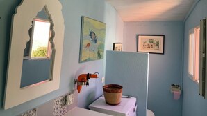 Une salle de bain avec un lavabo, un miroir, un tableau et une photographie encadrée accrochée au mur.