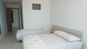 A hotel room with two single beds, a large bed, and a small table. - Pousada Praia de Guarajuba (Camaçari)