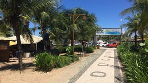 A paved pathway with palm trees and a sign for 'Condomínio Mar Azul'. - Pousada Praia de Guarajuba (Camaçari)