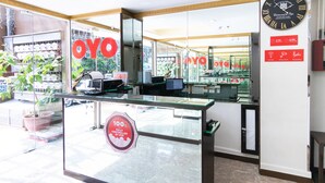 A reception desk with a glass partition, a clock, and a sign indicating a 100% fully controlled by OYO. - OYO 152 Sangco Condotel (Manila)