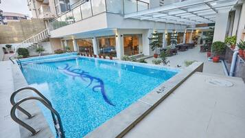 Una piscina al aire libre, sombrillas, sillones reclinables de piscina