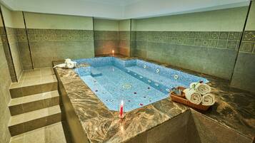 Relax in a luxurious spa area with a large hot tub, stairs, and marble countertop.