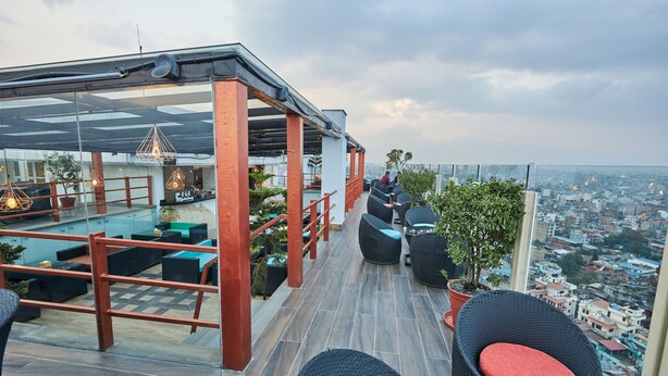 A rooftop terrace with outdoor seating, a pool, and a city view.