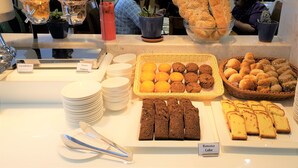 A buffet with various food items including bread, muffins, and cakes.