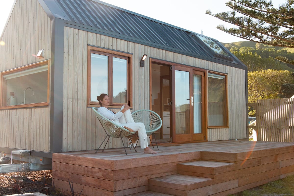A modern wooden house with a porch, large windows, and a sliding glass door.