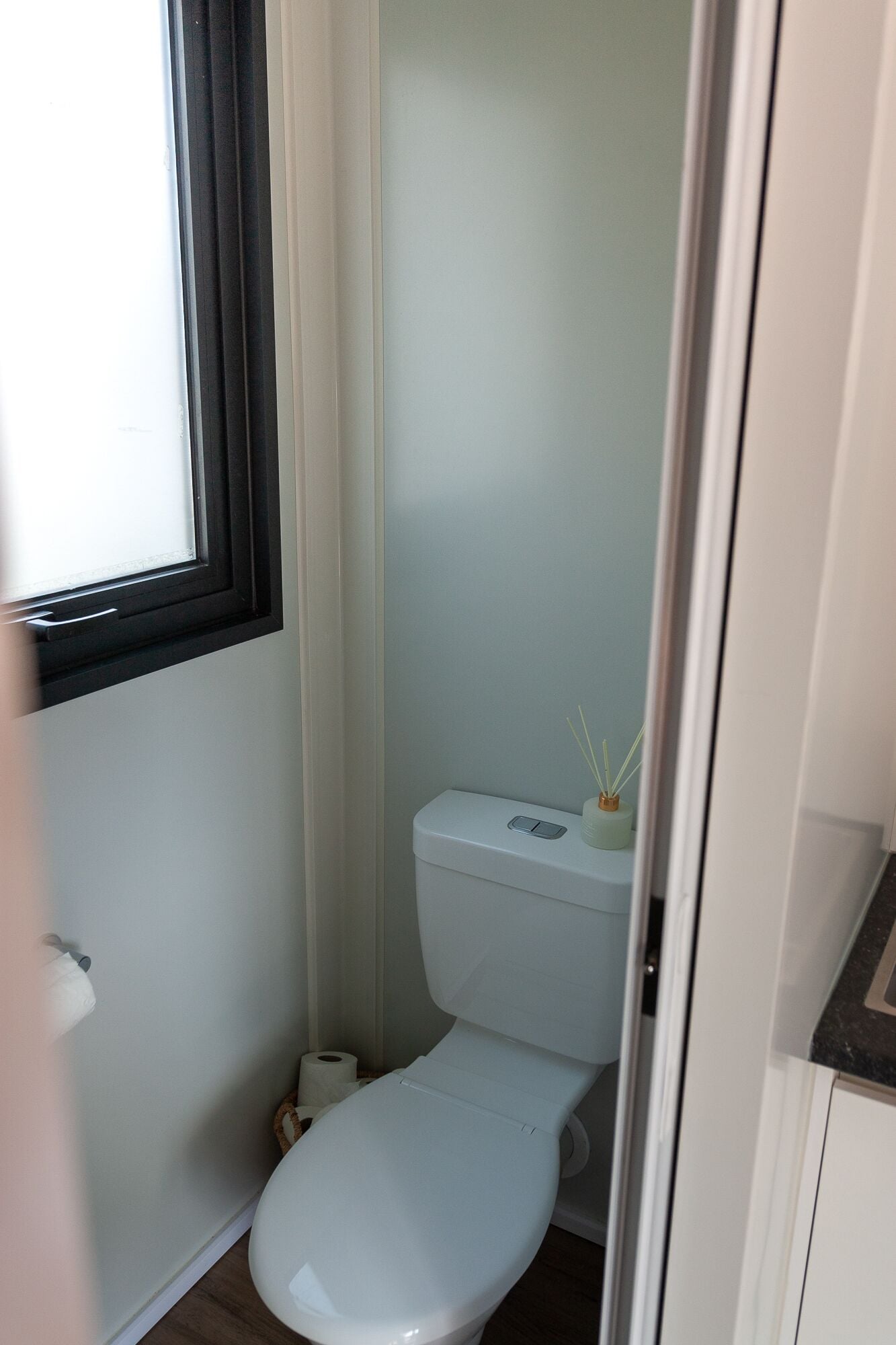 Ein kleines, kompaktes Badezimmer mit Toilette, Fenster und Waschbecken.