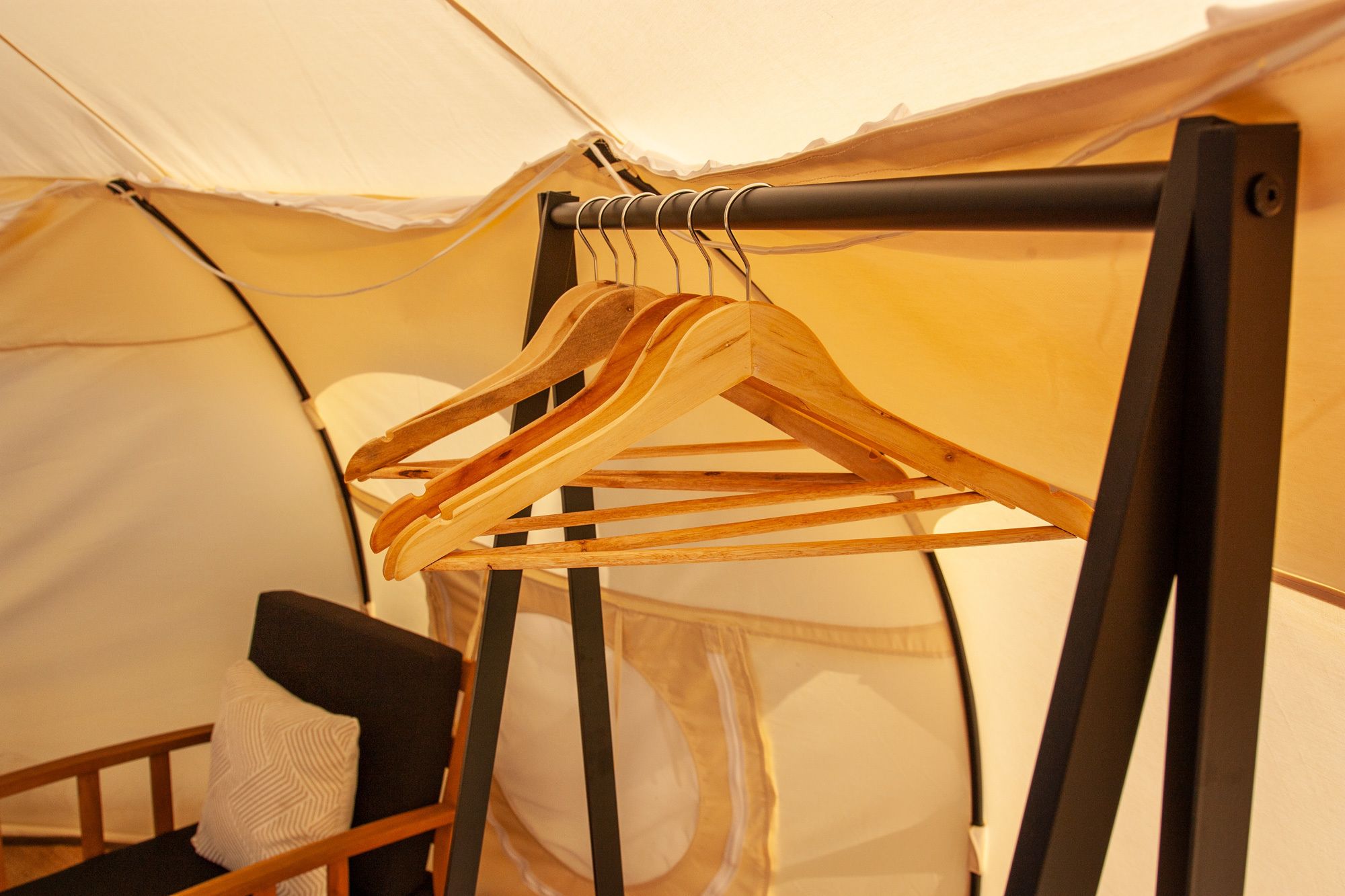 A tent with a wooden hanger rack holding several clothes hangers.