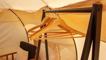 A tent with a wooden hanger rack holding several clothes hangers.