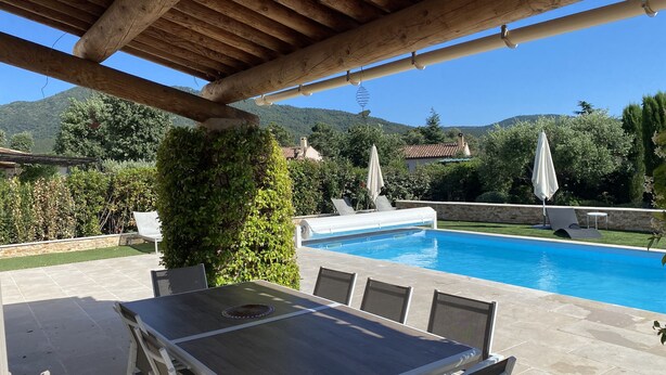 Ein überdachter Außenbereich mit Pool, Sitzgelegenheiten und Bergblick.