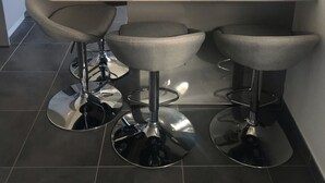 Eine moderne Küche mit Kochinsel, Edelstahlgeräten und Barhocker.