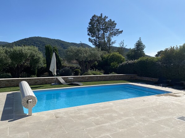 A rectangular swimming pool with a stone deck, a lounge chair, and a sun umbrella. - Detached Villa with Private Pool, Air-Conditioned (La Môle)