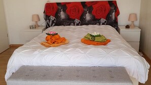 A neatly made bed with a white duvet and a grey bench at the foot. - Chez Minnie (La Grande-Béroche)