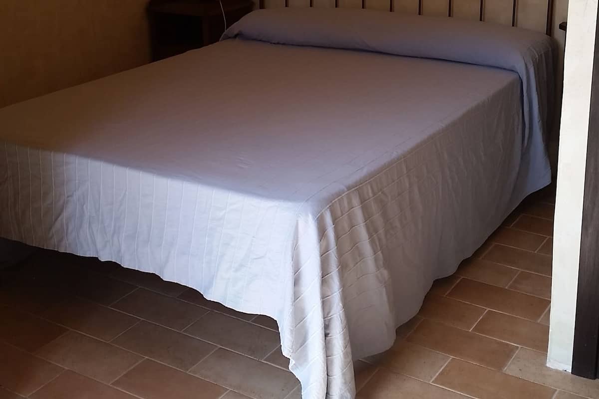 Une chambre à coucher avec un lit, une table de chevet, une lampe et un plafond en bois.