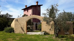Un bâtiment rustique doté d’une tour rouge et d’une arche en pierre qui mène à une cour intérieure.