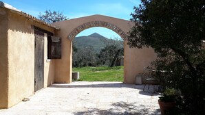 Une cour avec un sol en pierre, une arche en briques et une vue sur une montagne.