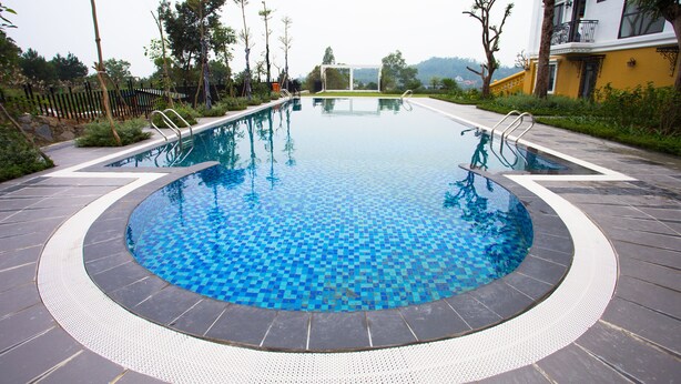 Una piscina con un estampado de baldosas a cuadros, rodeada por un suelo de piedra y una barandilla de metal.