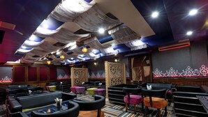 A restaurant with multiple tables and chairs, a patterned floor, and decorative ceiling drapes. - Hotel Celebration - Raipur (Raipur)