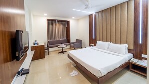 A hotel room with a large bed, a TV, a sofa, a small table, and a ceiling fan. - Hotel Celebration - Raipur (Raipur)