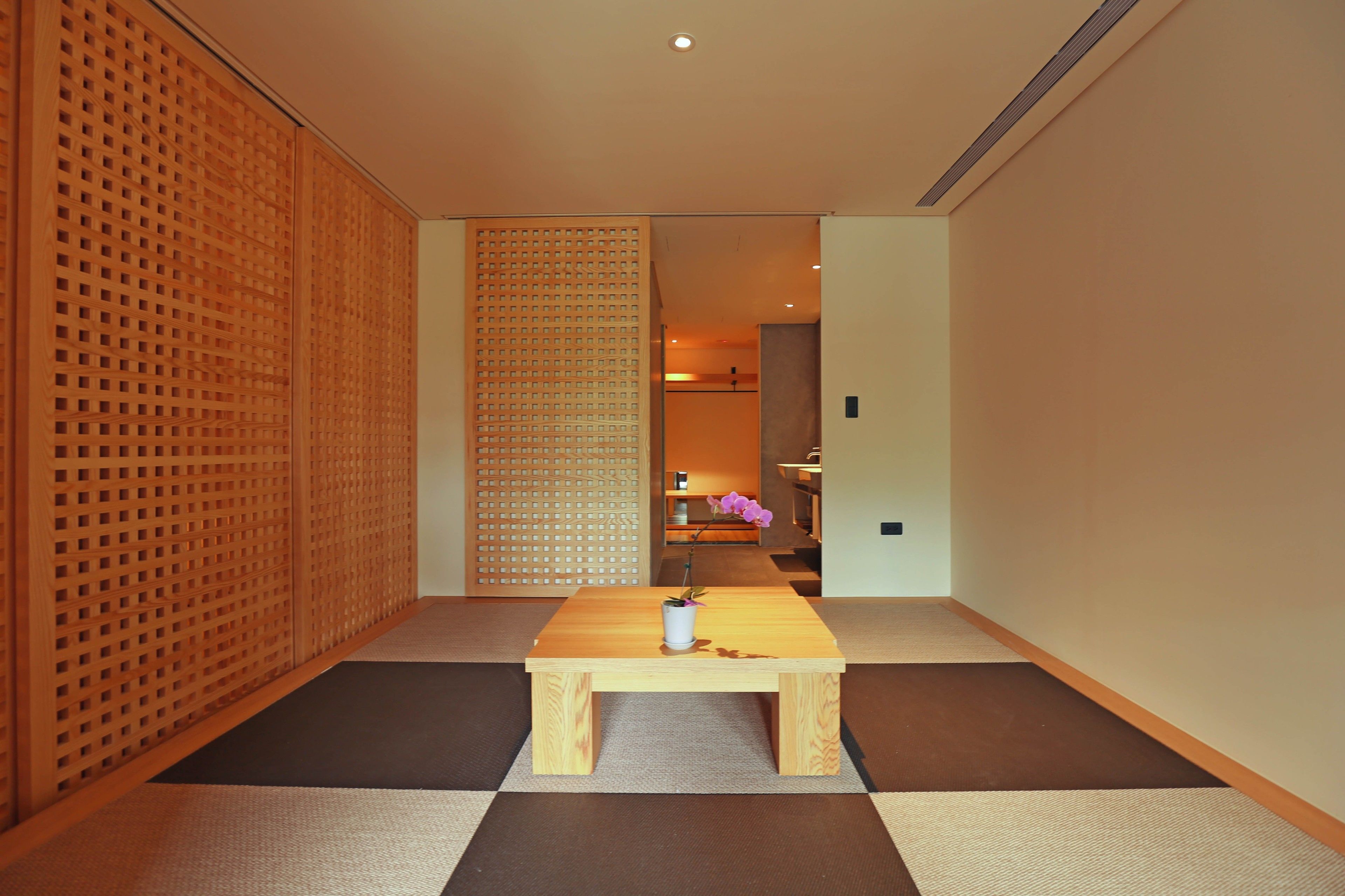 Um quarto japonês tradicional com tatames, uma mesa de madeira baixa e uma porta deslizante.
