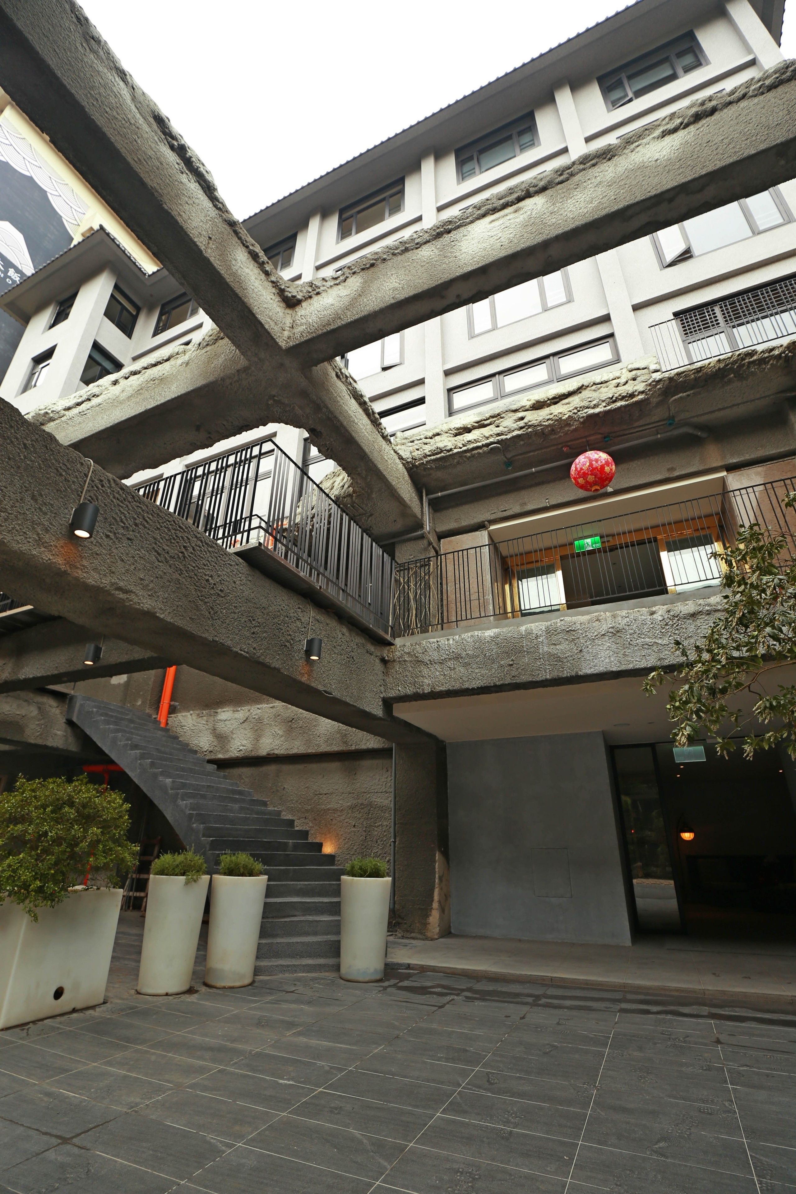 A multi-level building with a central staircase, outdoor seating area, and potted plants.