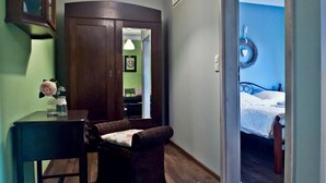 Une chambre à coucher avec un lit, une petite table sur laquelle est posé un vase, une chaise et une armoire.