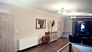 Un couloir avec un radiateur, une armoire en bois, un tableau encadré et un escalier menant à un espace détente.