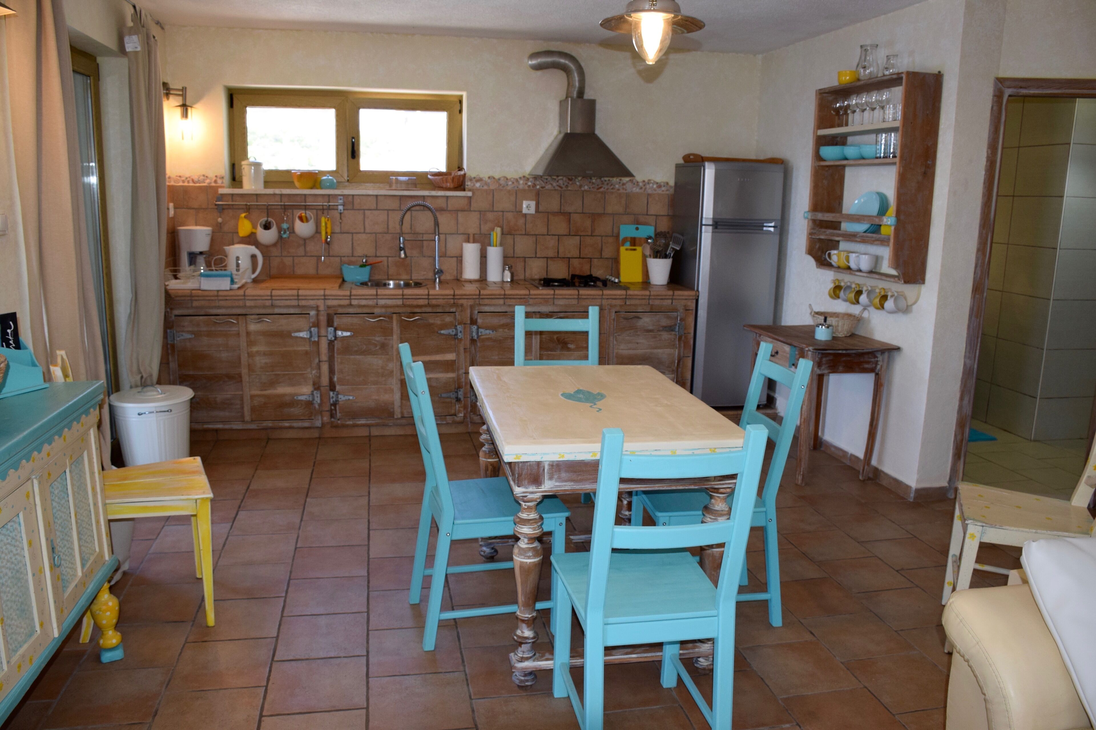 Una cocina con mesa y sillas, un lavamanos, una estufa y un refrigerador.